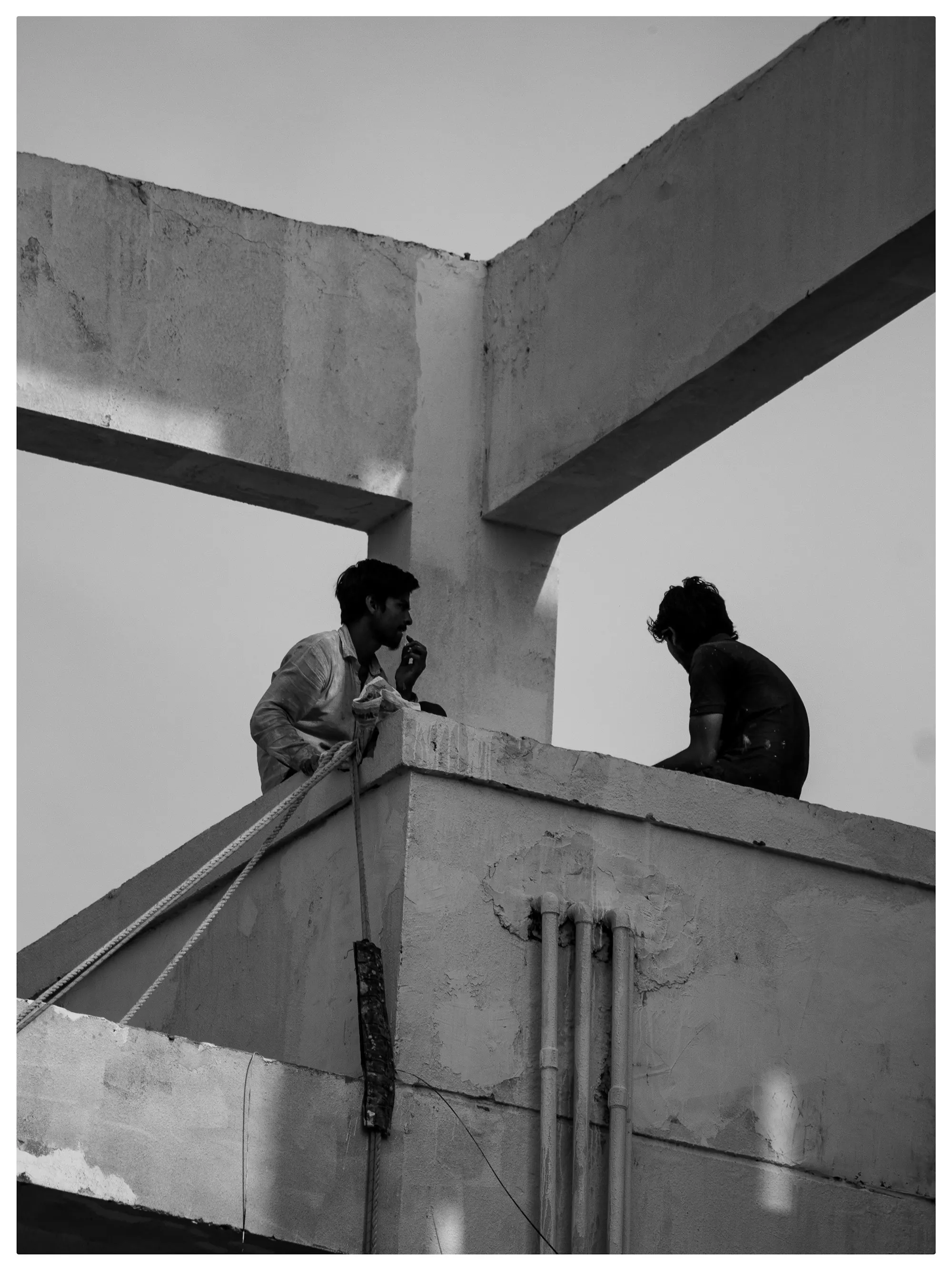 Two workers on the edge of a concrete slab under construction